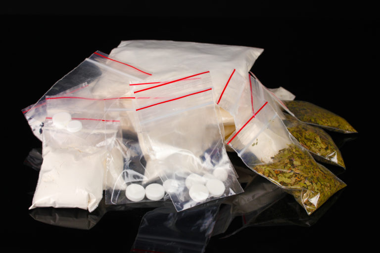 Cocaine and marijuana in packages on black background